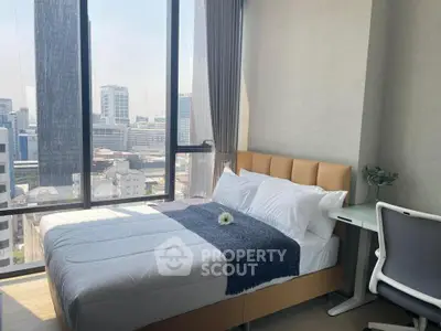 Modern bedroom with city view, featuring a cozy bed and sleek desk, perfect for urban living.