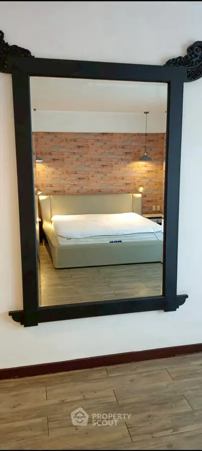 Stylish bedroom with modern decor and elegant mirror reflecting cozy ambiance.