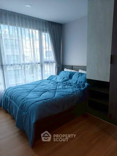 Cozy bedroom with large window and blue bedding in modern apartment