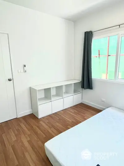 Bright minimalist bedroom with wooden flooring and modern storage unit