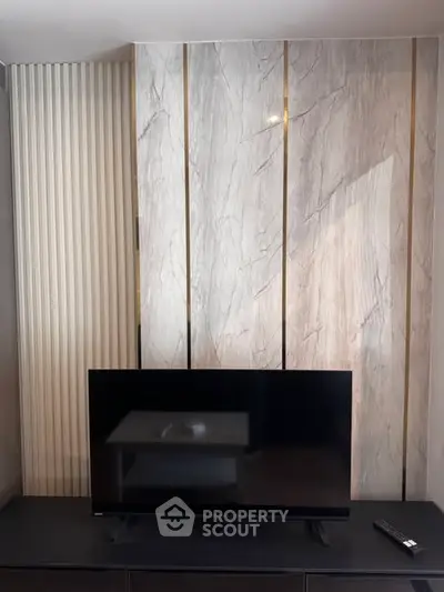 Modern living room with sleek TV setup and elegant marble wall design.