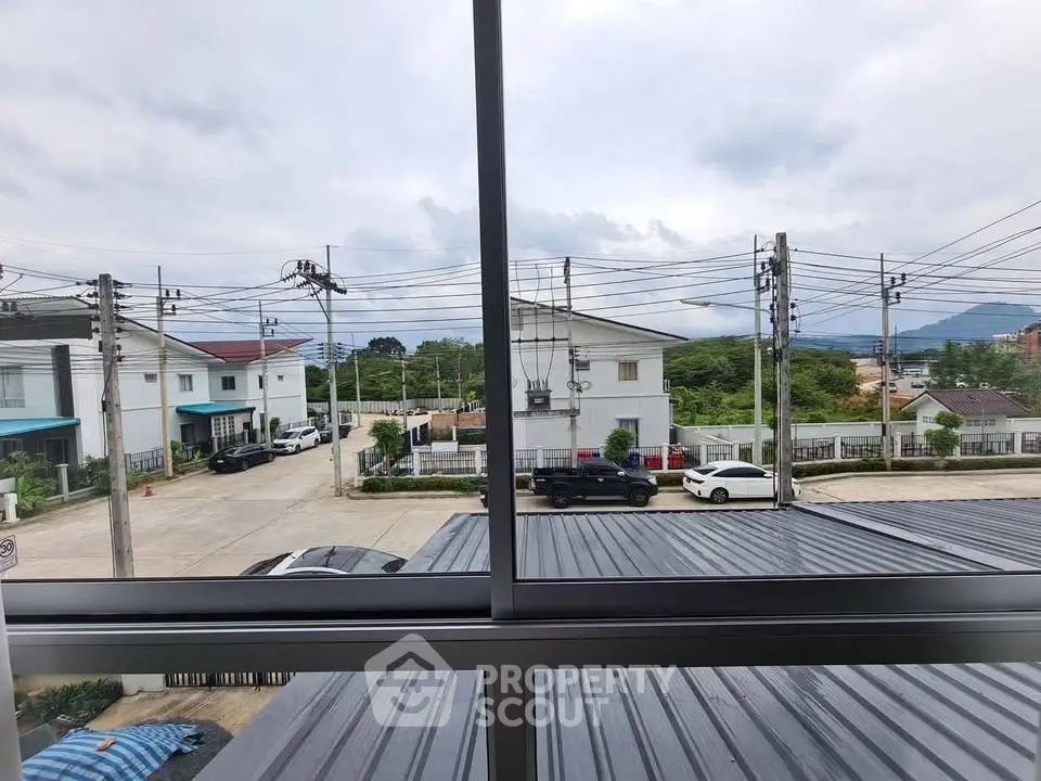 Scenic view from window overlooking residential neighborhood and distant hills.