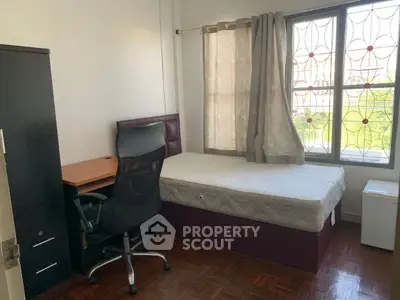 Cozy bedroom with single bed, study desk, and large window offering natural light.