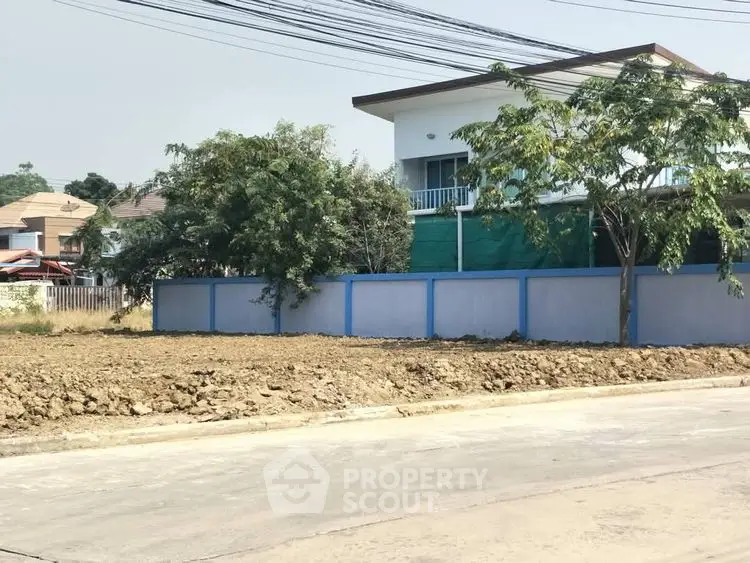 Vacant land plot with adjacent residential building, ideal for development.