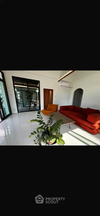 Spacious living room with modern red sofa and large windows offering natural light.