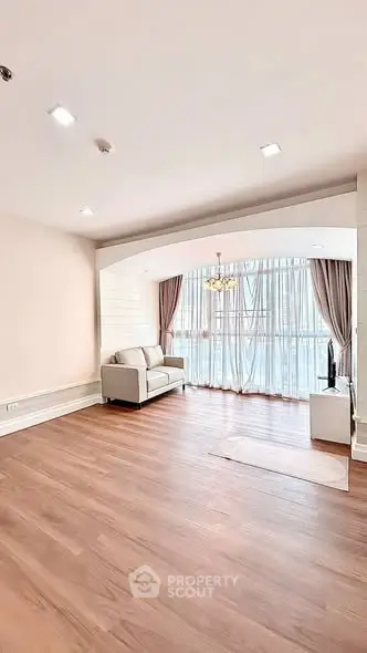 Spacious living room with elegant wooden flooring and large windows for natural light.