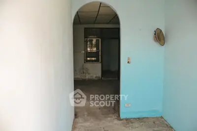 Spacious entryway with arch leading to a potential living area, featuring a rustic charm.