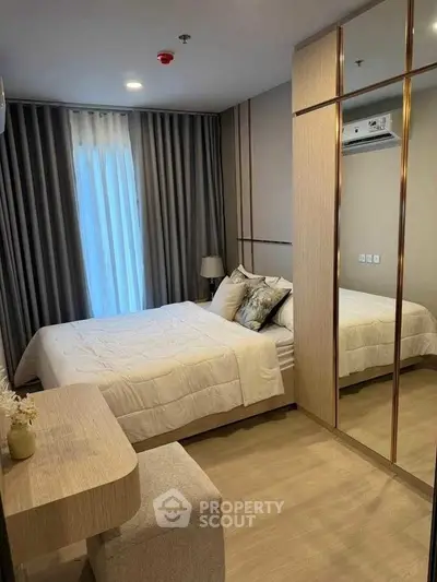 Modern bedroom with stylish decor and mirrored wardrobe in a cozy apartment.