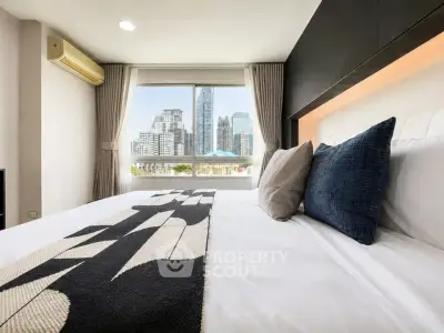 Modern bedroom with city view, featuring stylish decor and large window for natural light.