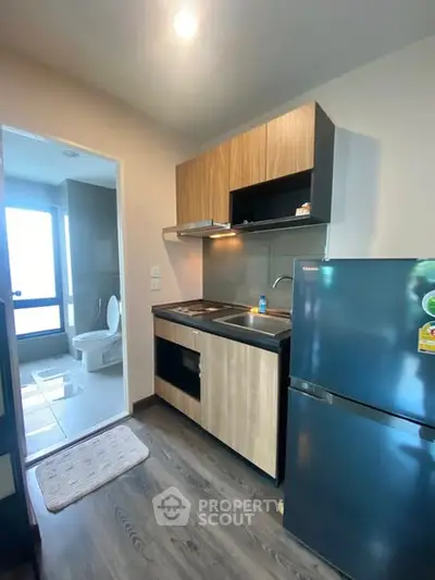 Modern compact kitchen with fridge and bathroom view