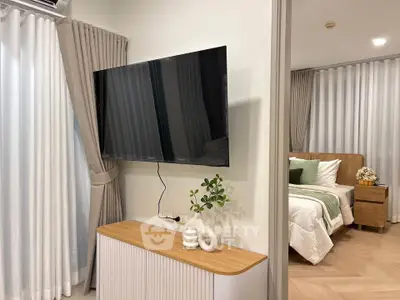 Modern bedroom with stylish decor and wall-mounted TV, featuring elegant curtains and cozy ambiance.