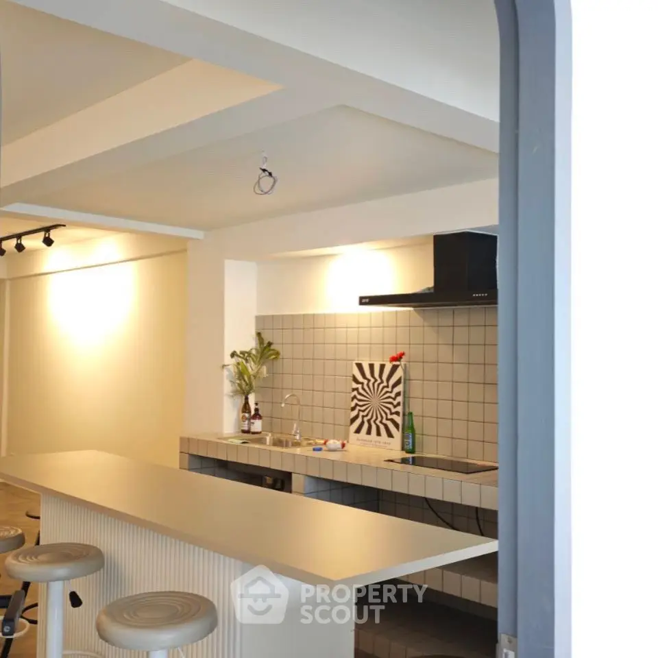 Modern kitchen with sleek design and open layout featuring stylish bar stools and contemporary decor.