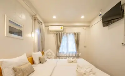 Cozy bedroom with twin beds, modern decor, and wall-mounted TV in a bright apartment.
