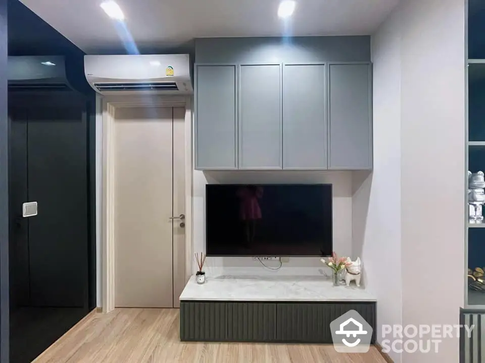 Modern living room with sleek built-in cabinetry and entertainment unit, complemented by warm wooden flooring and contemporary lighting.