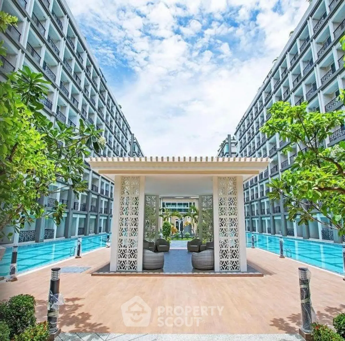 Luxurious modern building with stunning poolside view and elegant outdoor seating area.