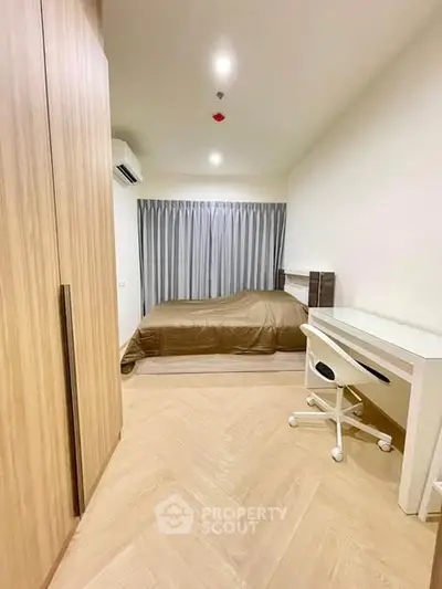 Modern bedroom with wooden flooring, cozy bed, and study desk in a stylish apartment.