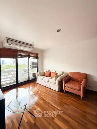 Spacious living room with hardwood floors and city view balcony in modern apartment.