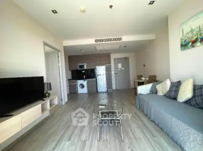 Modern living room with open kitchen, featuring sleek appliances and stylish decor.
