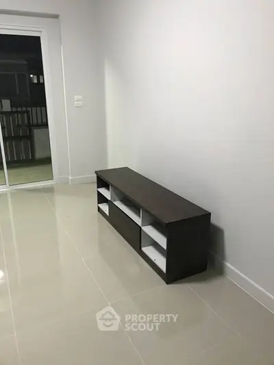 Spacious living room with modern TV stand and sliding glass doors to balcony.