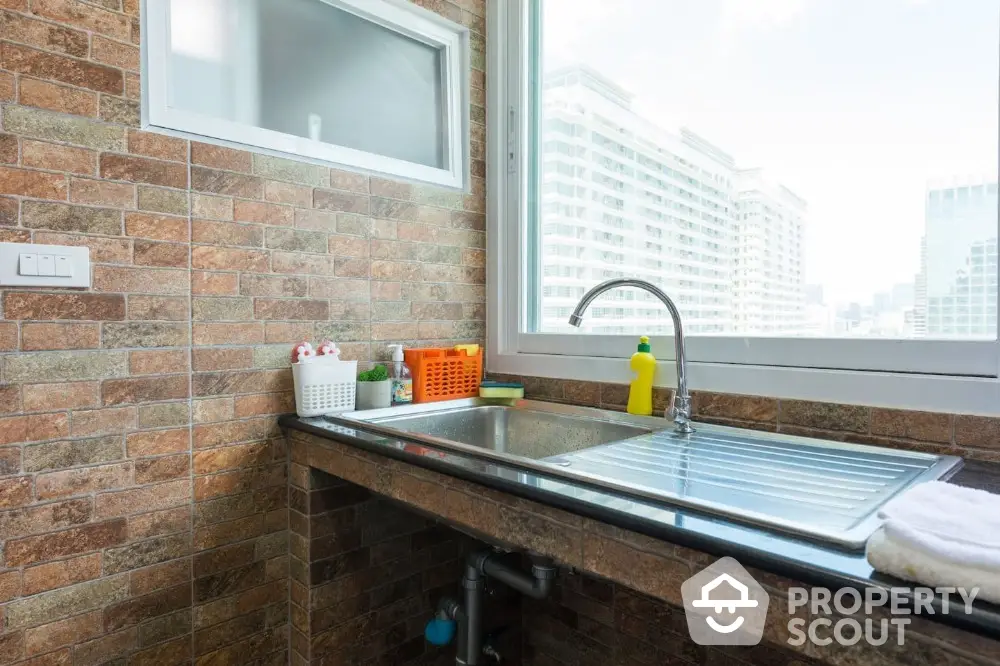 Modern kitchen with city view, featuring sleek sink and brick backsplash.