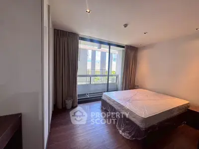 Spacious bedroom with large window and balcony view in modern apartment