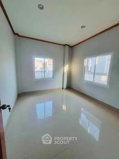 Spacious empty room with large windows and glossy tiled floor, perfect for customization.