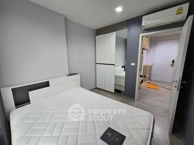 Modern bedroom with sleek design, featuring a comfortable bed, mirrored wardrobe, and air conditioning unit.