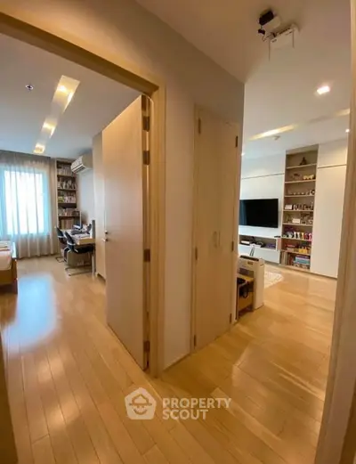 Spacious modern apartment with wooden flooring and built-in shelves, perfect for comfortable living.