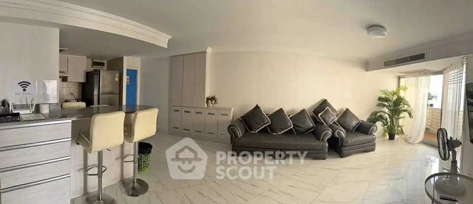 Spacious modern living room with open kitchen and balcony access, featuring sleek furniture and elegant decor.