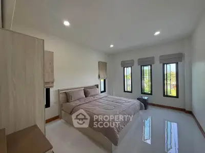 Spacious bedroom with modern decor and large windows offering natural light and garden views.