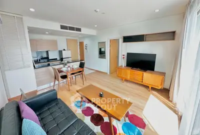Modern living room with open kitchen, stylish furniture, and vibrant decor in a bright apartment.