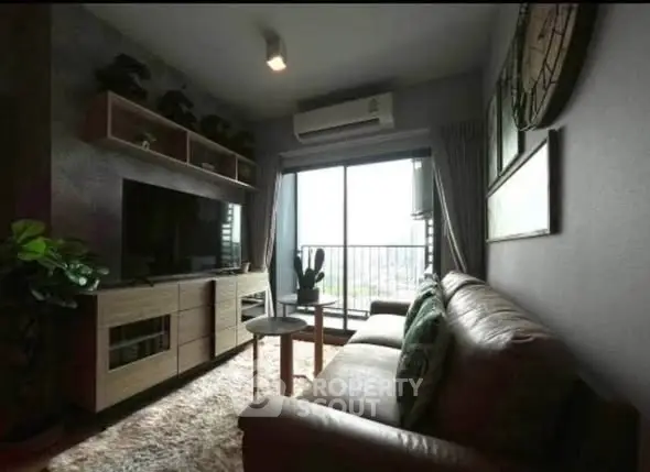 Cozy living room with modern decor and balcony view, featuring a comfortable sofa and entertainment center.