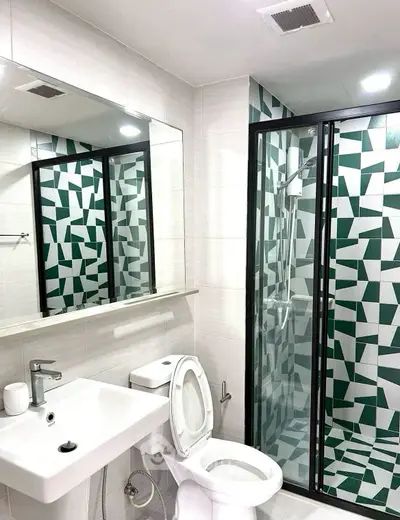 Modern bathroom with geometric tile design and glass shower enclosure.