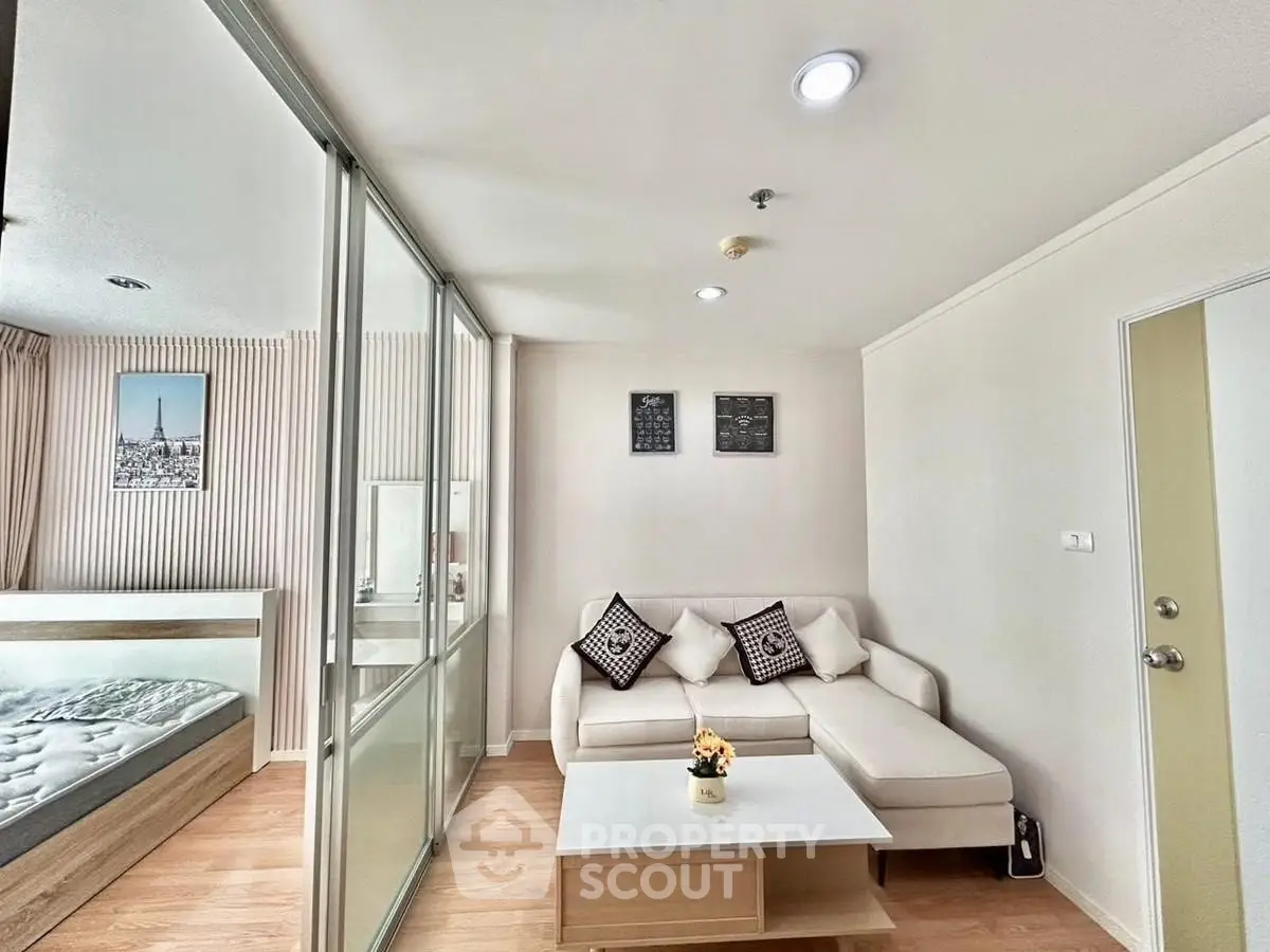 Modern living room with cozy sofa and glass partition to bedroom