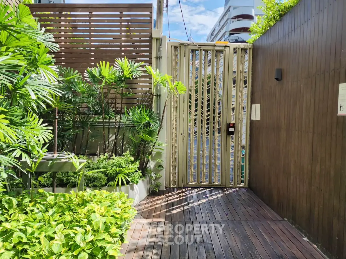 Modern gated entrance with lush greenery and wooden accents, offering a serene and secure ambiance.