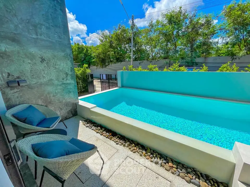 Charming outdoor pool area with modern seating and lush greenery