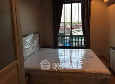 Cozy bedroom with large window offering city view, perfect for urban living.
