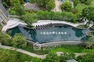 Luxurious aerial view of a modern swimming pool surrounded by lush greenery in a high-end residential complex.