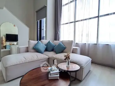 Spacious living room with large windows and modern decor, perfect for relaxation and entertaining.