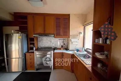 Charming kitchen with wooden cabinetry and modern appliances, featuring a cozy corner layout and ample natural light.