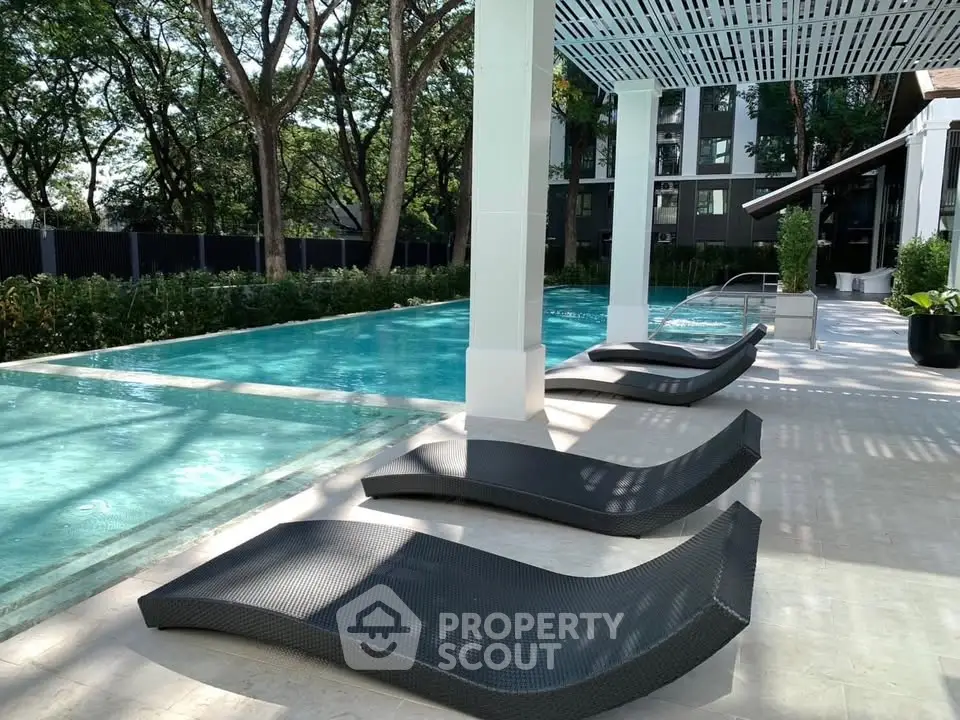 Luxurious outdoor pool area with stylish loungers and lush greenery in a modern residential complex.