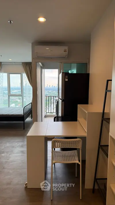 Modern apartment interior with city view, featuring a compact dining area and large windows.