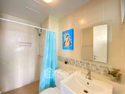 Modern bathroom with shower, sink, and stylish decor in a bright, tiled setting.