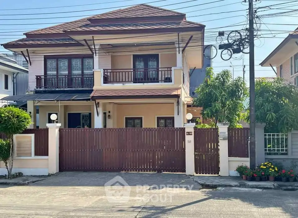 Charming two-story house with balcony and gated entrance in a serene neighborhood.