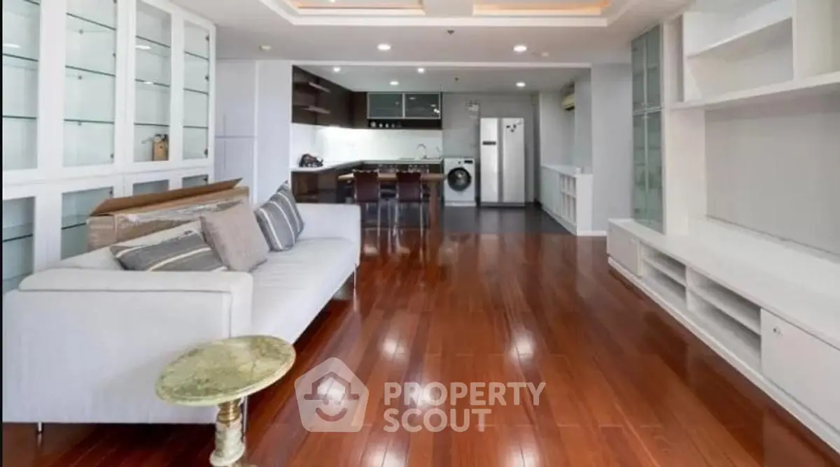 Spacious living room with sleek wooden flooring and modern kitchen in open layout