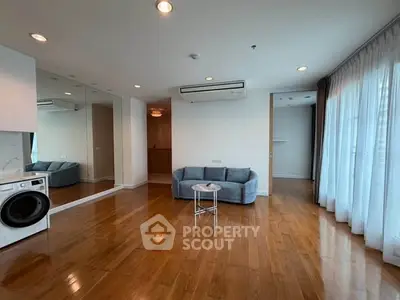 Spacious living room with hardwood floors, modern sofa, and large windows for natural light.