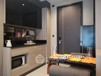 Modern kitchen with sleek cabinets and compact dining area in stylish apartment.