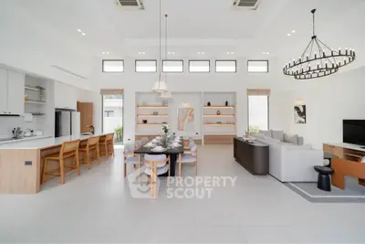Spacious modern living room with open kitchen and elegant dining area, featuring high ceilings and stylish decor.