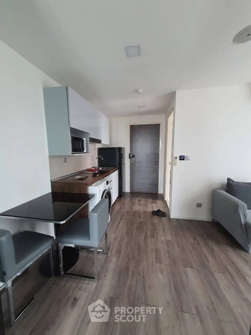 Modern apartment interior with sleek kitchen and cozy living area, featuring contemporary furniture and appliances.