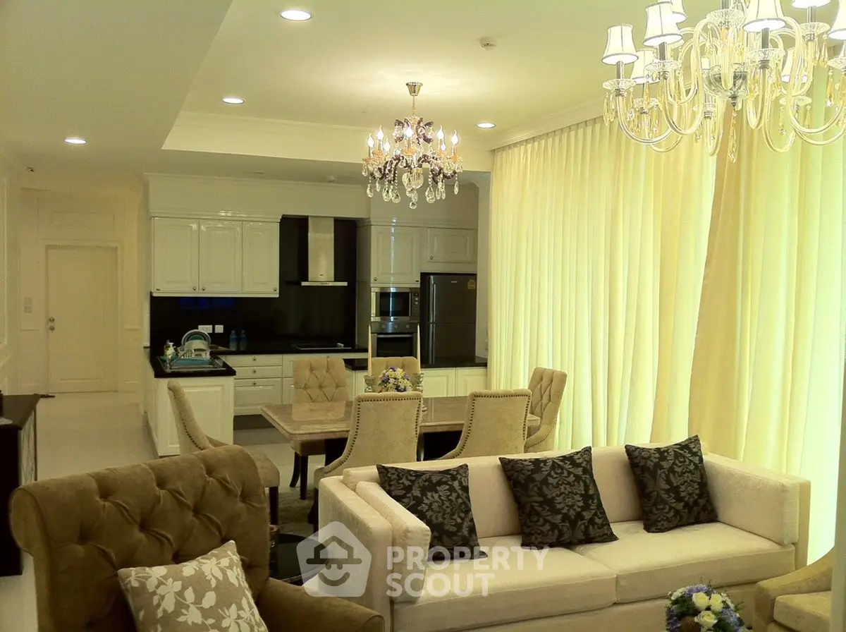 Luxurious open-plan living room with elegant chandelier and modern kitchen